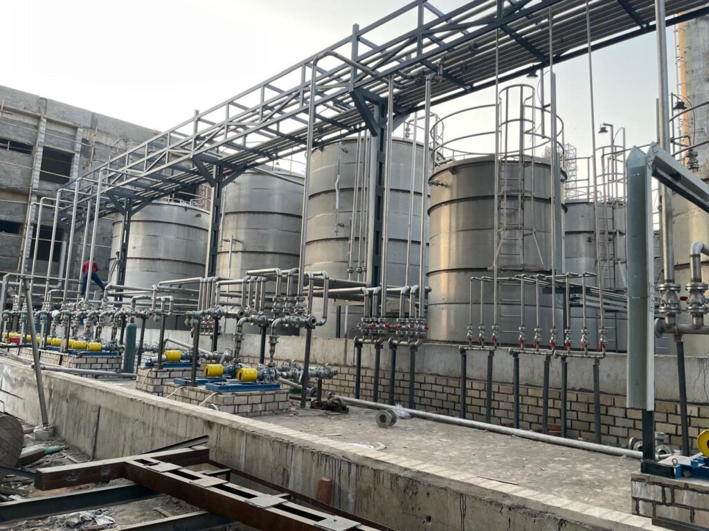 Storage tanks with pumps, valves and an overhead pipe rack